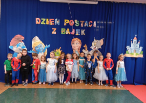 Na zdjęciu widzimy dzieci z grupy Odkrywcy pozujących na tle dekoracji i napisu „Dzień Postaci z Bajek”.