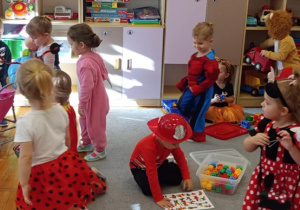 Biedronki w strojach karnawałowych bawią wspólnie bawiące się zabawkami przedszkolnymi.