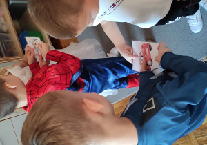 Dzieci stają w parach, trzymając w dłoniach pasujące do siebie połowy ilustracji z bajkowymi postaciami.