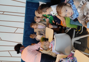 Dzieci siedzące przy stoliku w cukierni częstują się zakupionymi ciasteczkami.