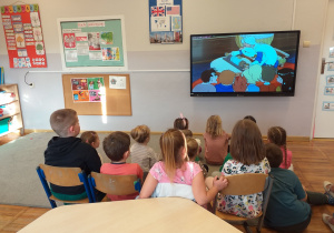 Zdjęcie przedstawia dzieci oglądające bajkę o wynalazkach.