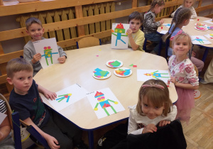 Zdjęcie przedstawia dzieci tworzące robota własnego pomysłu z gotowych figur geometrycznych.