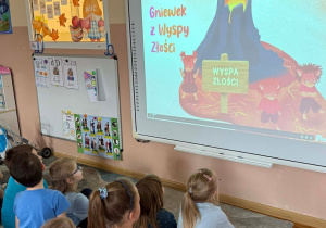 Dzieci oglądają na tablicy multimedialnej film dotyczący kolejnej postaci poznanej w projekcie.