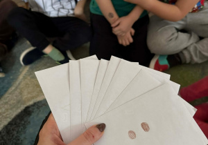 Nauczyciel trzyma przygotowane zadania dla zespołów.