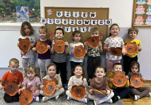 Grupa Stokrotki pozuje do wspólnego zdjęcia z pracami plastycznymi.