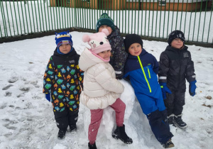 Dzieci pozują do zdjęcia przy dużej śniegowej kuli.