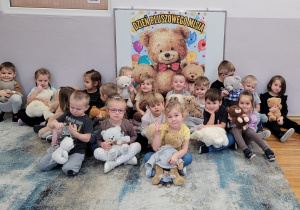Wspólna fotografia Słoneczek ze swoimi misiami na tle plakatu.