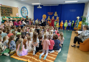 Zdjęcie przedstawia dzieci z grupy Odkrywcy przygotowane do występu, a nauczycielka zapowiada występ.