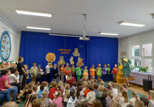 Zdjęcie przedstawia dzieci przebrane za różne owoce, warzywa i zwierzęta, a jedna z dziewczynek przebrana za śliweczkę deklamuje swój wierszyk.