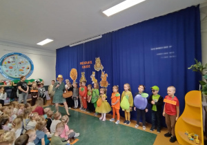 Zdjęcie przedstawia Panią Jesień przechadzającą się po lesie zgodnie ze słowami piosenki „Idzie lasem Pani Jesień”.