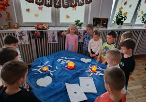 Dzieci z grupy „Misie” stoją przy „andrzejkowym stole wróżb”.