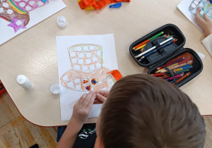 Chłopiec z grupy „Misie” wykonuje andrzejkową pracę plastyczną – Czarodziejski kapelusz.