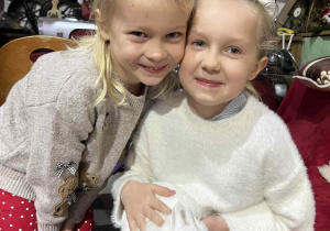 Dziewczynki pozują do zdjęcia z białym królikiem.