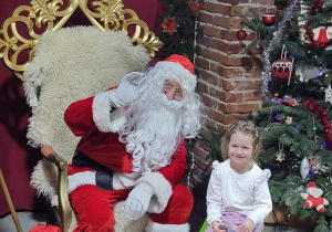 Dziewczynka pozuje do zdjęcia ze Świętym Mikołajem.