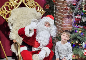 Chłopiec pozuje do zdjęcia ze Świętym Mikołajem.