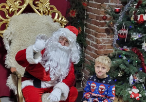 Chłopiec pozuje do zdjęcia ze Świętym Mikołajem.