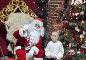 Dziewczynka pozuje do zdjęcia ze Świętym Mikołajem.