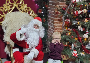 Chłopiec pozuje do zdjęcia ze Świętym Mikołajem.