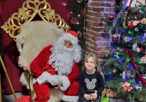 Dziewczynka pozuje do zdjęcia ze Świętym Mikołajem.