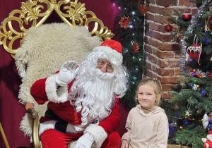 Dziewczynka pozuje do zdjęcia ze Świętym Mikołajem.