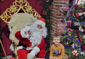Chłopiec pozuje do zdjęcia ze Świętym Mikołajem.
