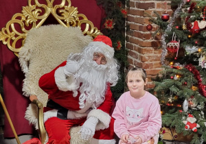 Dziewczynka pozuje do zdjęcia ze Świętym Mikołajem.