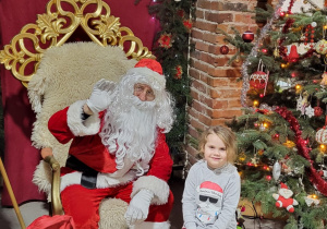 Dziewczynka pozuje do zdjęcia ze Świętym Mikołajem.