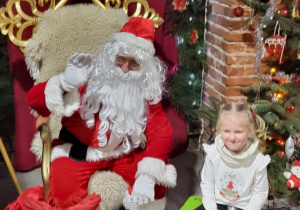 Dziewczynka pozuje do zdjęcia ze Świętym Mikołajem.