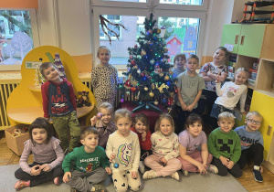 Dzieci z grupy Żabki pozują do zdjęcia z przystrojoną choinką.