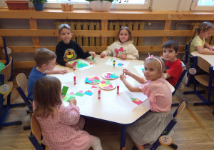 Zdjęcie przedstawia dzieci bawiące się w zabawę ruchową z figurami geometrycznymi.