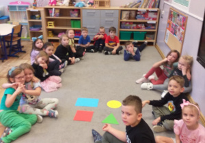 Zdjęcie przedstawia dzieci utrwalające poznane do tej pory figury geometryczne.