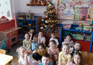 Dzieci pozują do zdjęcia z ozdobioną choinką