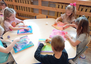 Na zdjęciu widzimy dzieci z grupy Odkrywcy podczas nawlekania kolorowej włóczki.