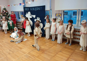 Zdjęcie przedstawia dzieci i jedno z dzieci przebrane za aniołka mówiące swoją kwestię.