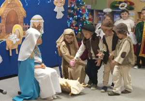 Trzej chłopcy przebrani za pasterzy przynoszą dary.