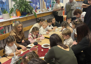 Dzieci z rodzicami podczas zdobienia pierników.