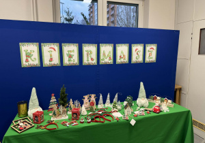 Na zdjęciu widać przygotowane stoisko z ozdobami świątecznymi i napisem Kiermasz.