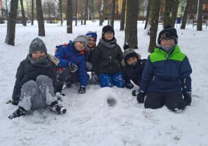 Chłopcy siedzą na śniegu z ich budowlą.