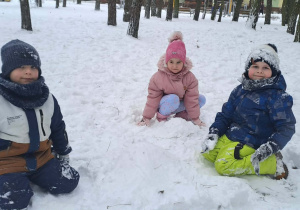 Dzieci robią orzełki/aniołki na śniegu.