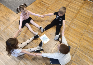 Dzieci układają płatki śniegu i swoimi ciałami robią śnieżynkę.