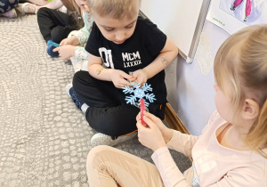 Dzieci podają sobie płatek śniegu przy pomocy klamerki.