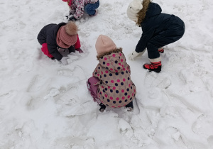 Dzieci lepią kulki ze śniegu.