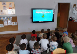 Dzieci oglądają film edukacyjny o śniegu wyświetlany na tablicy multimedialnej.