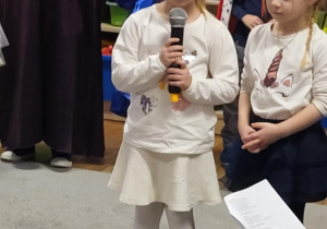 Dziewczynka z grupy Żabki recytuje wiersz z okazji Dnia Babci i Dziadka.