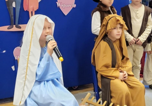 Dziewczynka z grupy Żabki recytuje wiersz z okazji Dnia Babci i Dziadka.