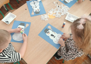 Dzieci wyklejają bałwanka.