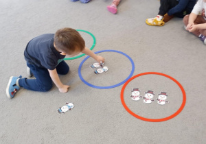 Chłopiec wkłada bałwanka do obręczy w kolorze niebieskim.