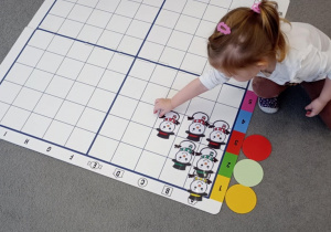 Dziewczynka układa bałwanki zgodnie z widzianą cyfra i kolorem koła.