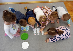Dzieci z grupy Biedronki układają bałwanki z kół różnej wielkości.