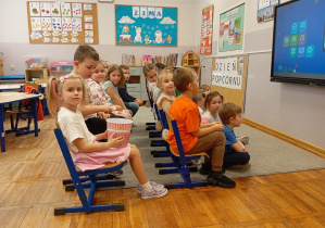 Dzieci z grupy Odkrywcy częstują się popcornem.